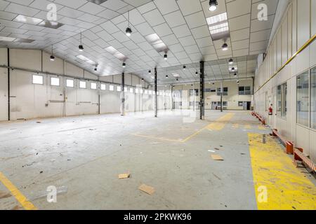 Geräumiges großes Zimmer für ein Lagerhaus oder einen Parkplatz mit Fenstern mit Metallsäulen und einer Decke, die für kosmetische Reparaturen vorbereitet ist. Das Konzept des Geschäfts Stockfoto