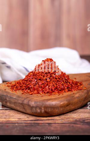 Getrocknete rote Pfefferflocken. Gewürze und Kräuter. Chilipfeffer ohne Samenflocken auf Holzhintergrund. Schließen Stockfoto