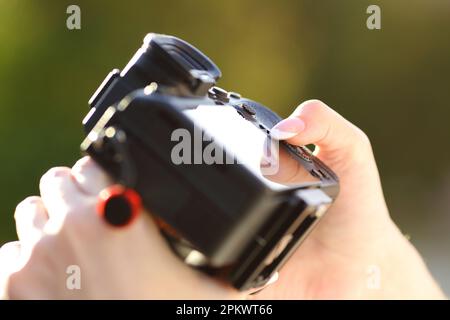 Nahaufnahme eines Fotografen, der die spiegellose Kamera in einem Park aufstellt Stockfoto