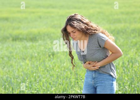 Frau mit Bauchschmerzen, die sich auf einem Feld beklagt Stockfoto