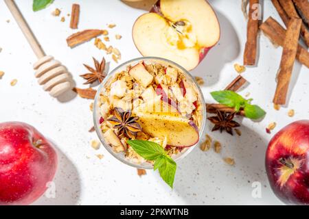 Apfelkuchen Müsli Käsekuchen, Frühstückssnack geschichtet Dessert mit Hafergranola, Frischkäse Joghurt, Honig, Apfelscheiben und Zimt Gewürze auf weiß Stockfoto