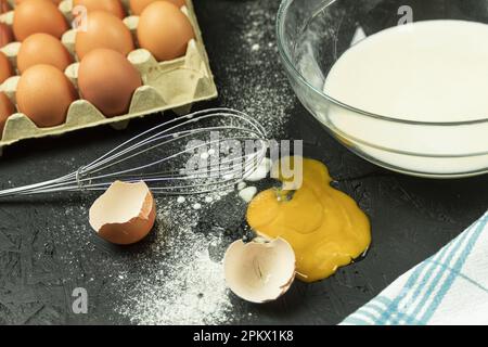 Ein zerbrochenes Ei auf dem Tisch, ein Chaos am Arbeitsplatz des Kochs. Hühnerei fiel auf den Tisch. Platz für Text Stockfoto