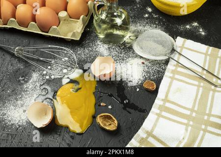 Ein zerbrochenes Ei auf dem Tisch, ein Chaos am Arbeitsplatz des Kochs. Hühnerei fiel auf den Tisch. Platz für Text Stockfoto