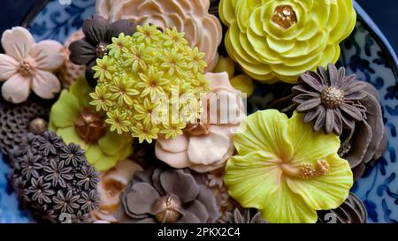 Aus nächster Nähe thailändisches Dessert mit verschiedenen Blumenformen und Geschmacksrichtungen, Mango, Orange, Schokolade, traditioneller thailändischer, handgefertigter Snack von Sam Pan Nee, Royal Famous Thai Swe Stockfoto