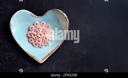 Kokosmilch-Geschmack, traditioneller thailändischer, handgefertigter Snack von Sam Pan Nee auf pastellblauer herzförmiger Platte, dunkler Hintergrund, königlich berühmtes thailändisches Süßigkeiten-Dessert Stockfoto