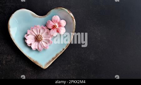 Kokosmilch-Geschmack, traditioneller thailändischer, handgefertigter Snack von Sam Pan Nee auf pastellblauer herzförmiger Platte, dunkler Hintergrund, königlich berühmtes thailändisches Süßigkeiten-Dessert Stockfoto