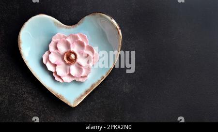 Kokosmilch-Geschmack, traditioneller thailändischer, handgefertigter Snack von Sam Pan Nee auf pastellblauer herzförmiger Platte, dunkler Hintergrund, königlich berühmtes thailändisches Süßigkeiten-Dessert Stockfoto