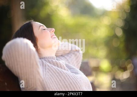 Profil einer entspannten Frau, die auf einer Bank im Park ruht Stockfoto