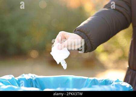 Nahaufnahme einer Frau, die im Winter in einem Park Müll in den Papierkorb wirft Stockfoto