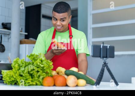 Junger lateinamerikanischer Food-Blogger Streaming Video Clip über das Kochen von gesundem Essen mit Tomaten und Kartoffeln und Salat Stockfoto