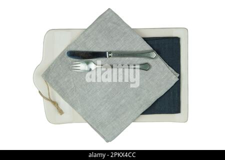 Gabel mit Messer und Küchenbrett mit einer Leinenserviette und einem Messer mit einer isolierten Gabel auf weißem Hintergrund. Draufsicht. Stockfoto