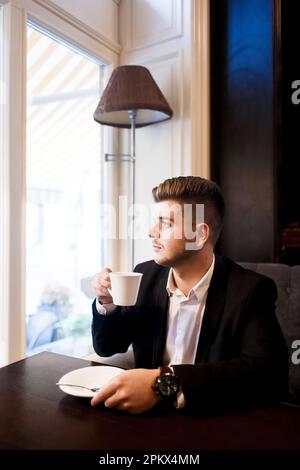 Ein junger Mann im Anzug trinkt Kaffee bei einem Geschäftstreffen Stockfoto