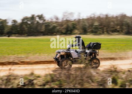 Ein beeindruckendes Foto von einem Mann, der auf einem Quad auf dem Land fährt Stockfoto