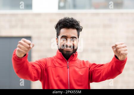 Junger Mann mit roter Jacke und Armbewegung Stockfoto