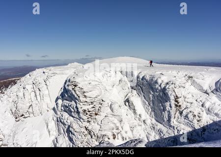 Skifahrer im Hinterland über schneebedeckten Klippen Stockfoto