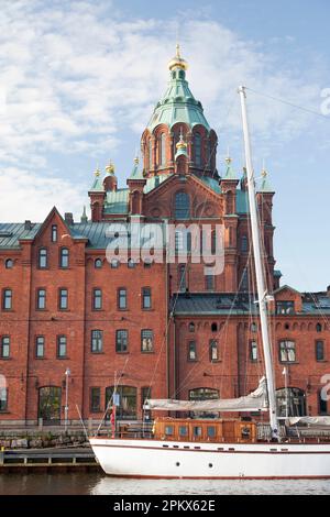 Finnland, Helsinki, Uspenski Orthodoxe Kathedrale, mit Yacht im Vordergrund. Stockfoto