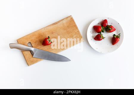 Messer mit Erdbeeren liegt auf einem Holzbrett in der Küche Stockfoto