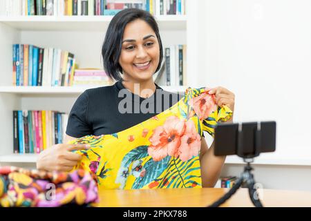 Lachende reife weibliche Influencer, die Video online mit dem Handy streamt Stockfoto