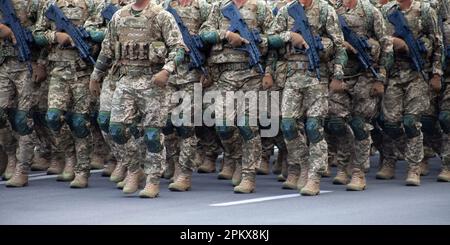 Militärsoldaten marschieren mit Waffen in eine Parade. Pixelgleichförmig. Soldatenbeine. Kriegshintergrund. Stiefel von Spezialeinheiten und Infanterie. Männer gehen an die Macht Stockfoto