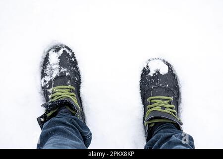 Männerfüße in Stiefeln in tiefem Schnee, Draufsicht. Stockfoto