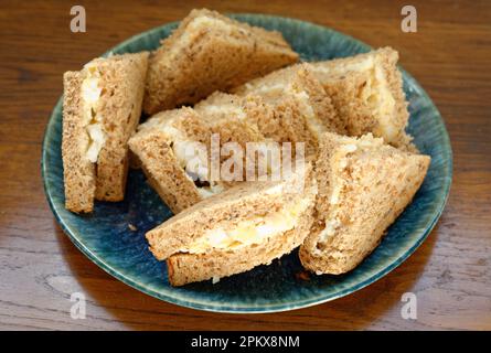 Ein Teller mit Mayonnaise-Sandwiches. Braunes Brot ohne Krusten. Stockfoto