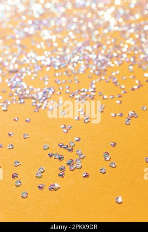 Glänzende silberne Kristallkonfetti auf gelbem Hintergrund. Selektiver Fokus. Stockfoto