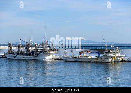 Japanische Fischerboote im Hafen von Rausu, Hokkaido, Japan. Die Insel Kunashir liegt im fernen Hintergrund. Stockfoto