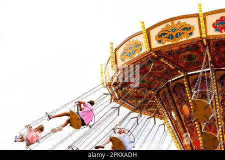 Kinder genießen eine klassische Fahrt auf dem „Flying Sessels“-Messegelände. Stockfoto