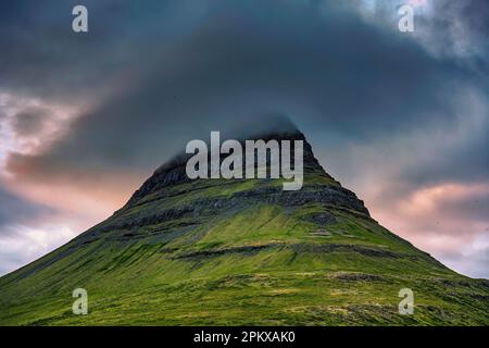 Nahaufnahme des Berggipfels Moody Kirkjufell mit Mützenwolken bedeckt im Sonnenuntergang im Sommer in Island Stockfoto