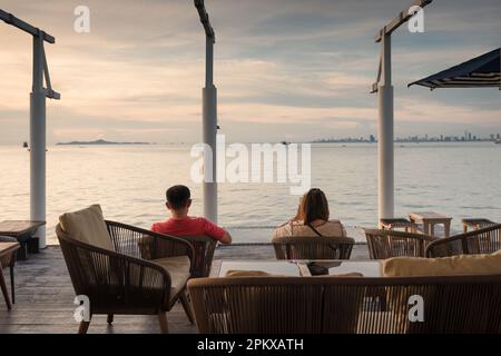 Erwachsene Rentnerpaare sitzen im Freien und entspannen sich abends auf der Terrasse am tropischen Meer Stockfoto