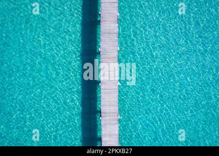 Blick von oben auf den hölzernen Pier auf dem türkisfarbenen Meer auf der tropischen Insel an sonnigen Tagen Stockfoto