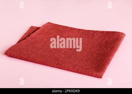 Draufsicht mit roter leerer Serviette auf Tischhintergrund isoliert. Gefaltetes Tuch für Modell mit Kopierbereich, flach liegend. Minimalistischer Style. Stockfoto