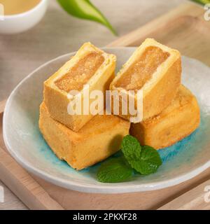 Köstliches taiwanesisches Ananaskuchen Gebäck auf einem Teller auf Holztisch mit heißem Tee. Stockfoto