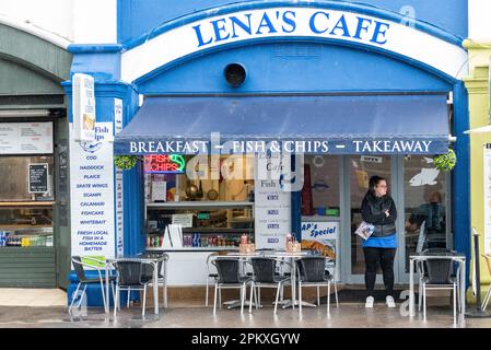 Southend on Sea, Essex, Großbritannien. 10. April 2023. Der Feiertag in Southend auf See hat den ganzen Morgen Regen gesehen. Die Sicherheitsmaßnahmen wurden eingerichtet, um eine traditionelle Zusammenkunft von Motorrädern zu verhindern, die den Fischern an der Küste sonst geholfen hätte, Geschäfte zu machen. Eine Frau draußen im Pier Arches Café, die nach Kunden sucht Stockfoto