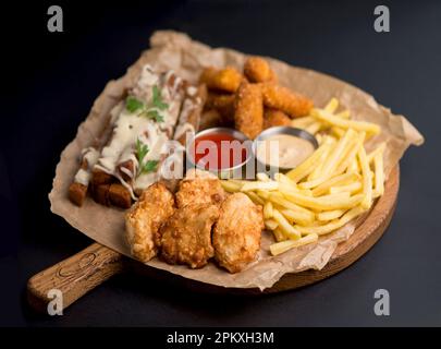 Große Auswahl an Snacks für Bier mit verschiedenen Soßen auf Pergament, Ansicht von oben Stockfoto