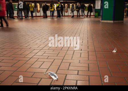 Bild einer alten Einweg-Gesichtsmaske auf dem Boden, in einer Straßenbahn und U-Bahn öffentlichen Verkehrsstation in Dortmund, Gerany, während des Coronavirus cr Stockfoto