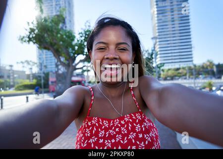 Wunderschöne junge afroamerikanische Frau, die Selfie im Freien am Stadtstrand macht. Stockfoto