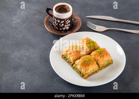 Traditionelles Pistazienbaklava mit türkischem Kaffee auf schwarzem Hintergrund, Draufsicht Stockfoto