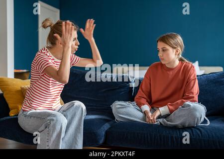 Junge, wütende, emotionale Mutter schreit die gestörte Teenagertochter zu Hause an Stockfoto