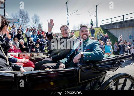 Traunstein, Deutschland. 10. April 2023. Bayerns Ministerpräsident Markus Söder (CSU, M) und der Bezirksverwalter von Traunstein Siegfried Walch (r) sitzen während der traditionellen Georgi-Fahrt am Ostermontag in einer Ehrenkutsche, während Hunderte festlich dekorierter Pferde durch das Oberbayerische Dorf zur Kirche Ettendorf fahren. Kredit: Uwe Lein/dpa/Alamy Live News Stockfoto