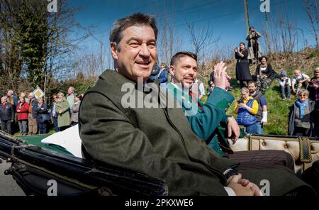 Traunstein, Deutschland. 10. April 2023. Bayerns Ministerpräsident Markus Söder (CSU, l) und der Bezirksverwalter von Traunstein Siegfried Walch (r) sitzen während der traditionellen Georgi-Fahrt am Ostermontag in einer Ehrenkutsche, während Hunderte festlich dekorierter Pferde durch das Oberbayerische Dorf zur Kirche Ettendorf fahren. Kredit: Uwe Lein/dpa/Alamy Live News Stockfoto