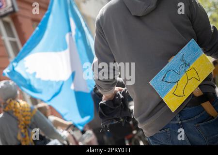 10. April 2023, Hessen, Frankfurt/Main: Ein Mann mit einem Schild mit den Nationalfarben der Ukraine und einer an seinem Gürtel befestigten Taube des Friedens nimmt an einem ostermarsch Teil. Auch im Jahr 2023 fanden unter dem Eindruck des russischen Krieges gegen die Ukraine zahlreiche Ostermärsche im ganzen Land statt. Foto: Sebastian Christoph Gollnow/dpa Stockfoto