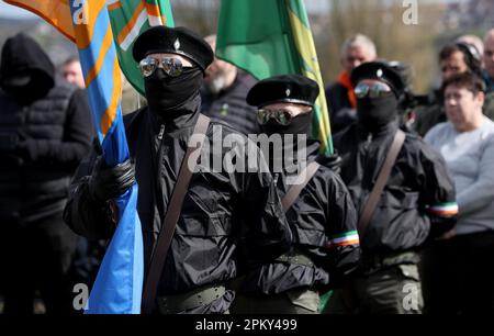 Mitglieder der Farbenpartei hören einem Redner während einer Parade der Dissidenten der Republikaner im Creggan-Viertel von Londonderry am Ostermontag zu. Die Behörden haben die Sicherheitsmaßnahmen als Reaktion auf die nicht gemeldeten Paraden in Derry erhöht. Foto: Montag, 10. April 2023. Stockfoto