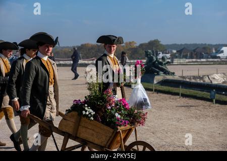 Viktorianisches Zeitalter Frankreich: Männliche Diener in eleganter Kleidung mit Blumen in den Gärten des Schlosses Versailles Stockfoto