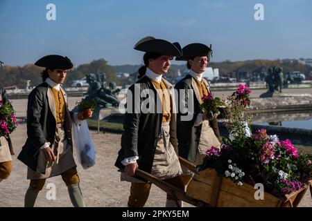 Viktorianisches Zeitalter Frankreich: Männliche Diener in eleganter Kleidung mit Blumen in den Gärten des Schlosses Versailles Stockfoto