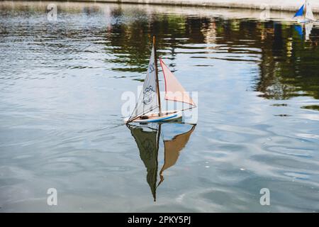 Spielzeug Segelboot mit verspieltem Gesicht Design Segel anmutig auf einem Pariser Garten Teich Stockfoto