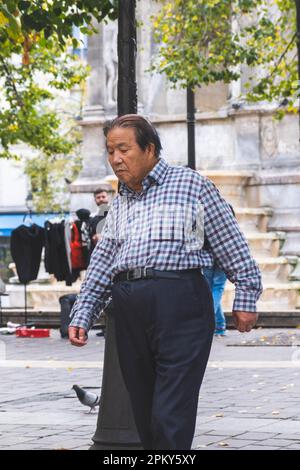 Ein älterer Chinese schlendert durch die bezaubernden Straßen von Paris und bewundert die Sehenswürdigkeiten und Klänge der Stadt der Liebe Stockfoto