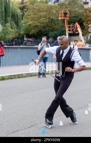 Black man in 1940er-Kleidung Rollerblading mit Schnurrbart auf einer Pariser Brücke, faszinierende Zuschauer Stockfoto