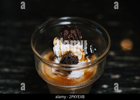 Nahaufnahme eines Glases Eiscreme mit Kaffee und zusätzlichen Brownies. Unscharfer Hintergrund. Stockfoto