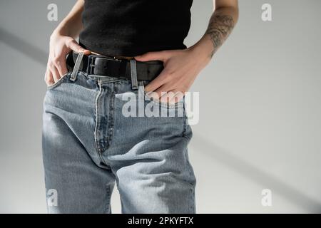 Schnittbild einer Frau in Jeans auf grauem Hintergrund Stockfoto